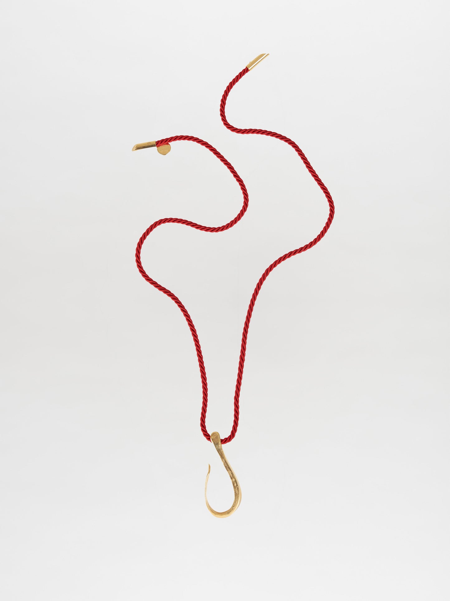 Silvia Tcherassi’s Frida Necklace Red features a red braided string and gold hook, beautifully displayed on a white background, perfect for layering with any outfit.