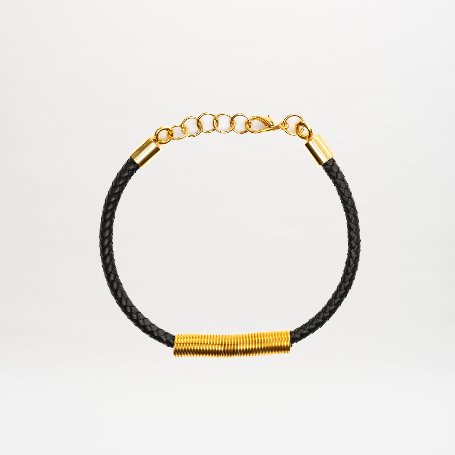 The Hadria Necklace by SVT DESIGNS features a black braided band, gold wire-wrapped accent, an adjustable gold chain clasp, and elegant gold embellishments, displayed on a plain white background.