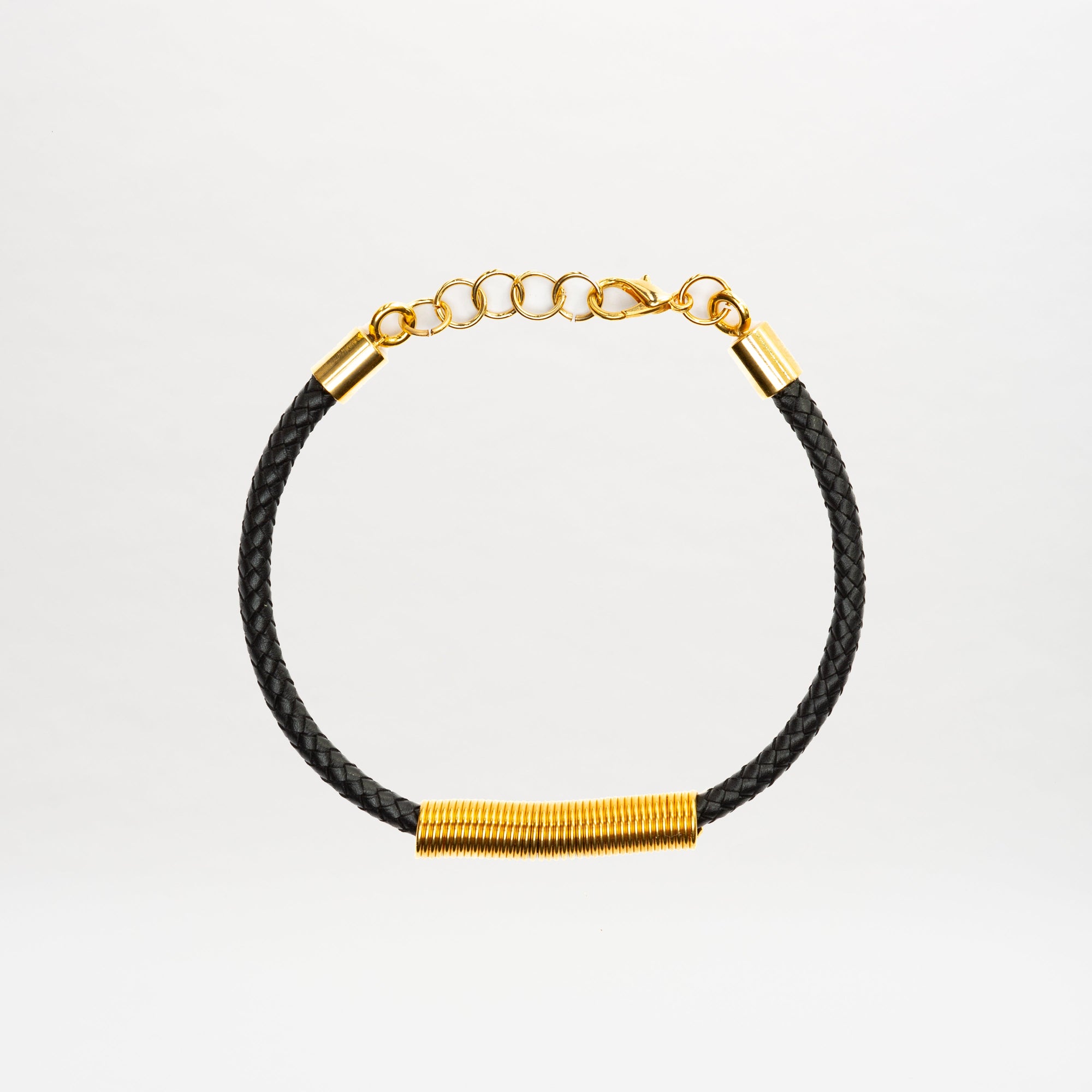 The Hadria Necklace by SVT DESIGNS features a black braided band, gold wire-wrapped accent, an adjustable gold chain clasp, and elegant gold embellishments, displayed on a plain white background.