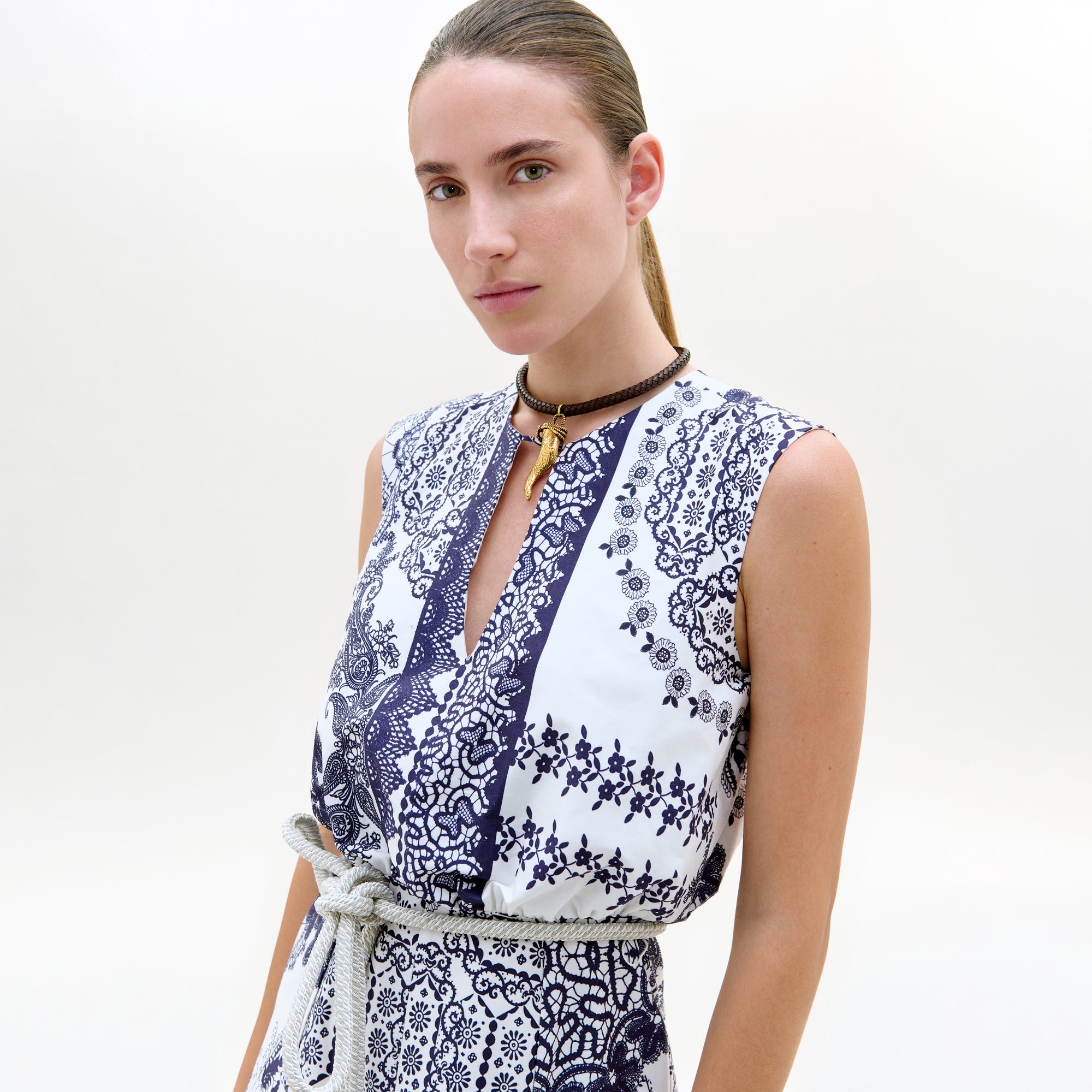Woman wearing a sleeveless dress with blue floral pattern on a white background