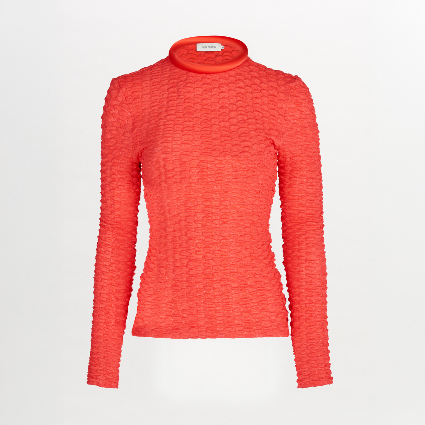 The Jari Top from Resort 2024 features a bright red embossed jacquard fabric, long sleeves, a fitted silhouette, mock turtleneck, and subtle circular pattern, displayed on a plain white background.