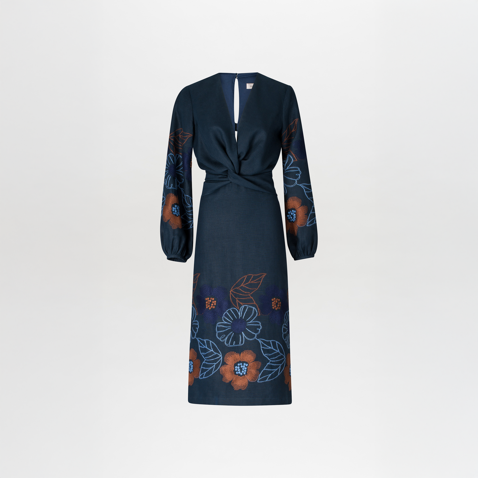 A person stands against a blue background wearing the Laoise Dress in Navy Ochre Flower Embroidery, paired with beige high-heeled sandals, perfect for an August 19th or September 2nd outing.