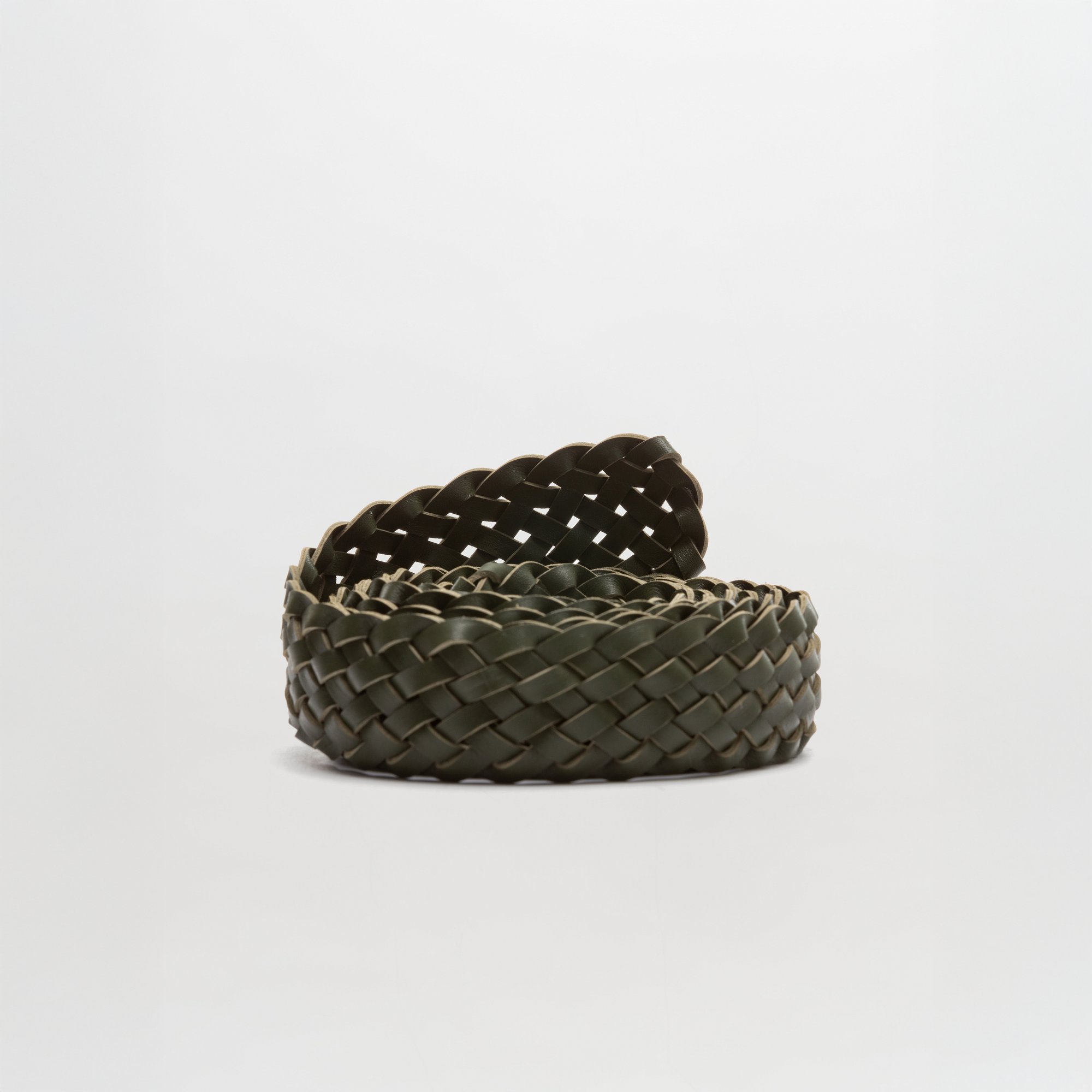 The Lauren Belt by SVT DESIGNS is a woven dark green braided Italian leather belt, coiled on a plain white background. It features a detailed braided pattern and no visible buckle.