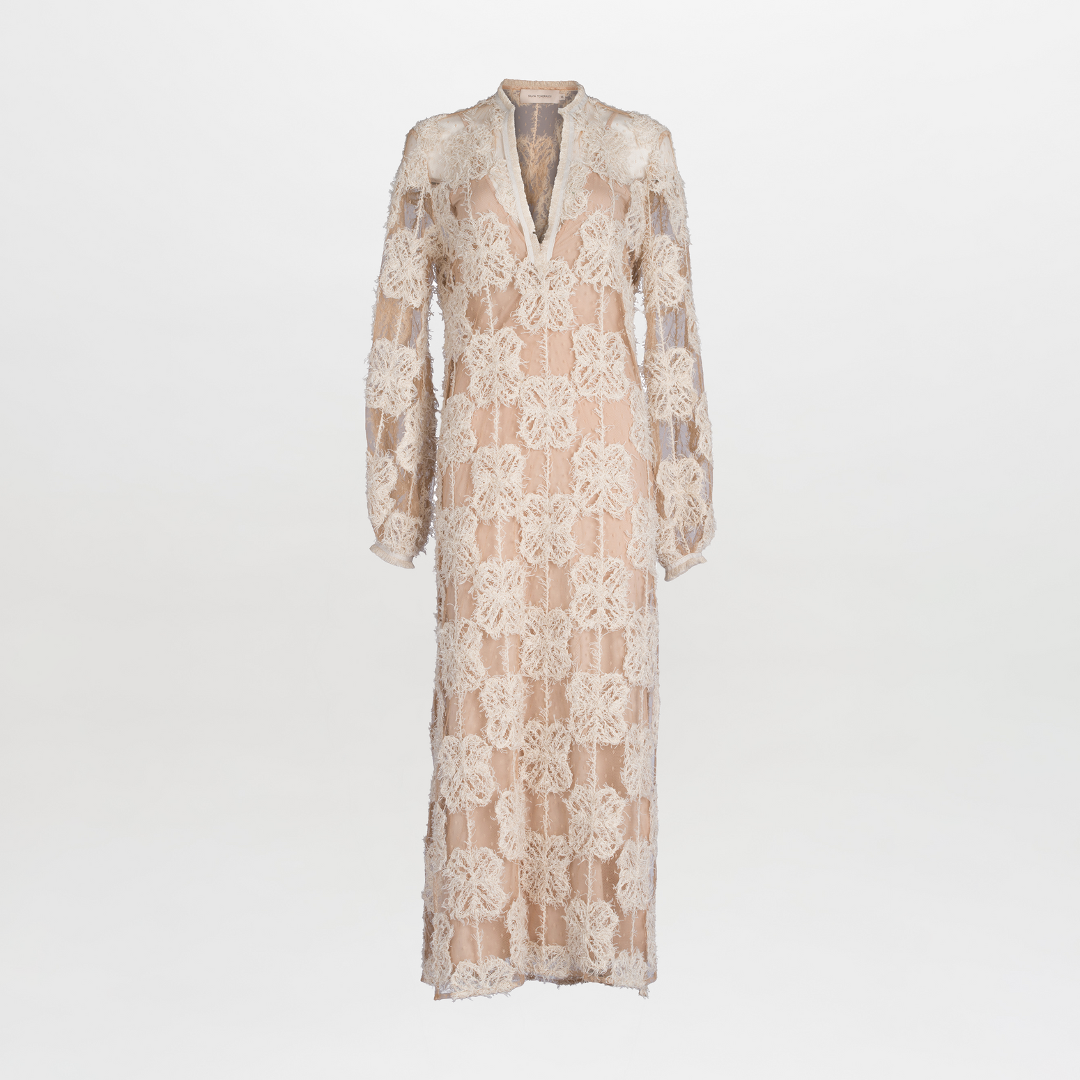 The Mayfair Tunic by SVT DESIGNS is a long, sheer beige maxi tunic featuring a deep V-neck, long sleeves, and intricate geometric and large floral cream-colored lace applique, offering striking contrast. It is elegantly presented against a plain white background.