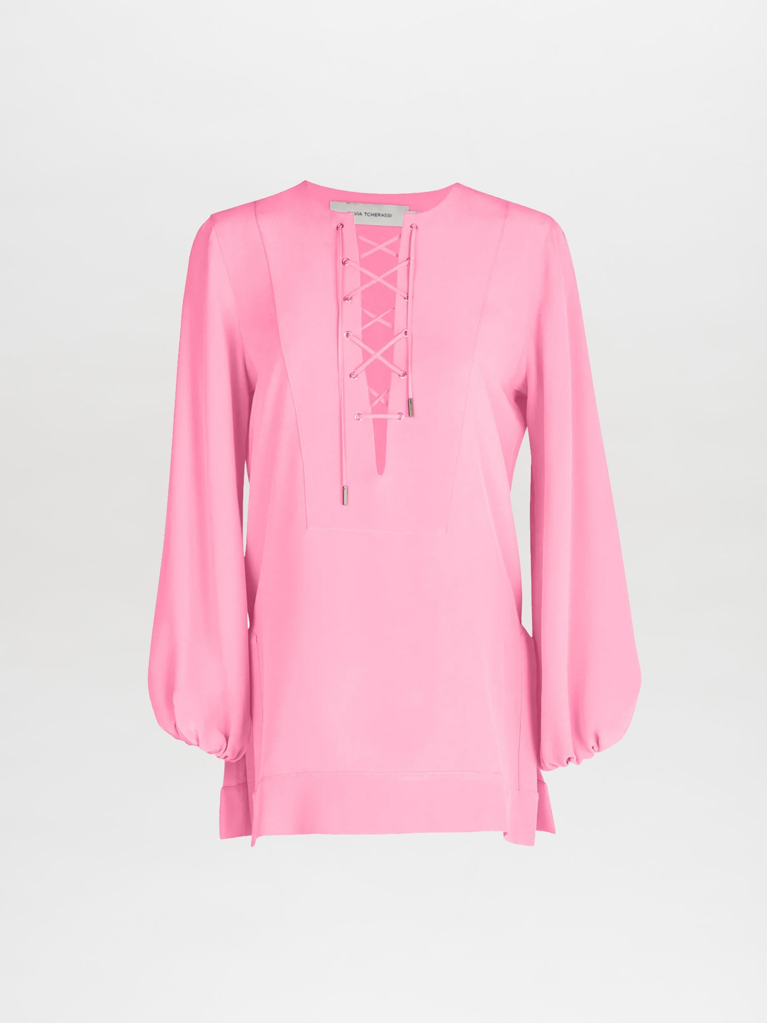 The Merve Blouse by Silvia Tcherassi features a v-shaped lace-up neckline and long, loose sleeves in pink silk, exuding casual glamour against a plain white background.