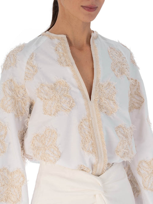 A Molveno Blouse Cream Flowers with long sleeves and golden floral motifs, isolated on a white background.