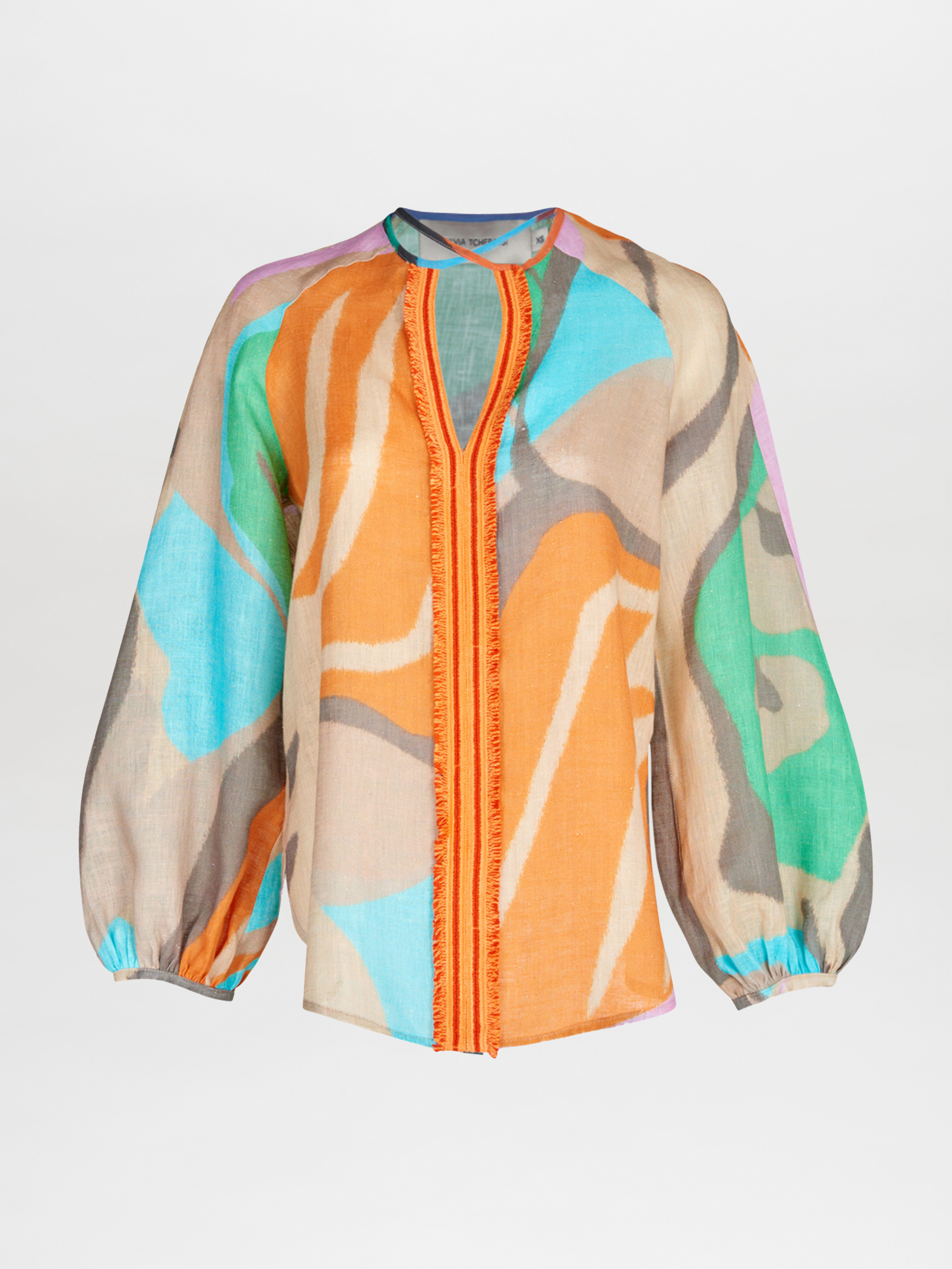 The Silvia Tcherassi Molveno Blouse is a loose-fit, long-sleeved top with casual glamour, showcasing a bold abstract print in orange, turquoise, green, purple, and beige. An open front with orange trim enhances its unique style.