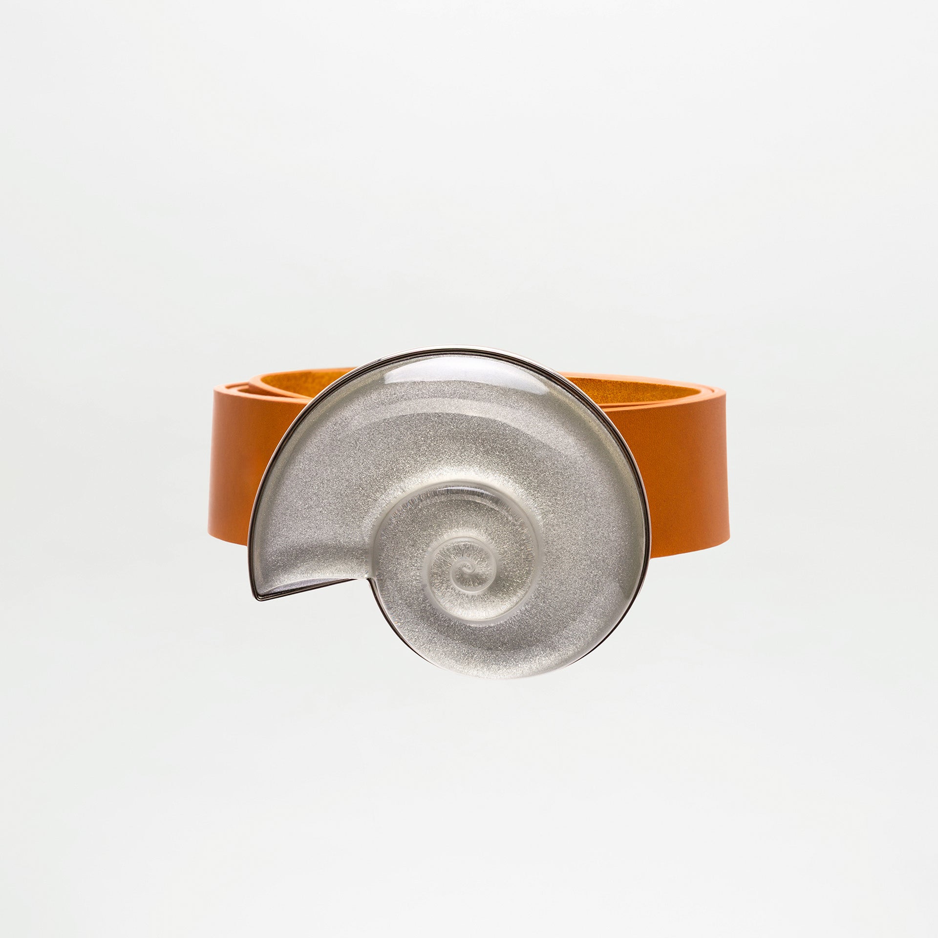 The SVT DESIGNS Nautilus Belt, crafted from 100% brown leather, features a large metallic spiral clasp inspired by a nautilus shell, shown against a plain white background.