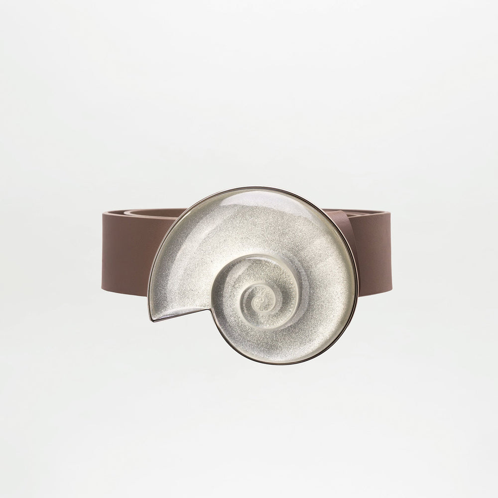 The Nautilus Belt by SVT DESIGNS features brown Italian leather and a large, metallic spiral seashell buckle with a fantasy stone, showcased against a plain white background.