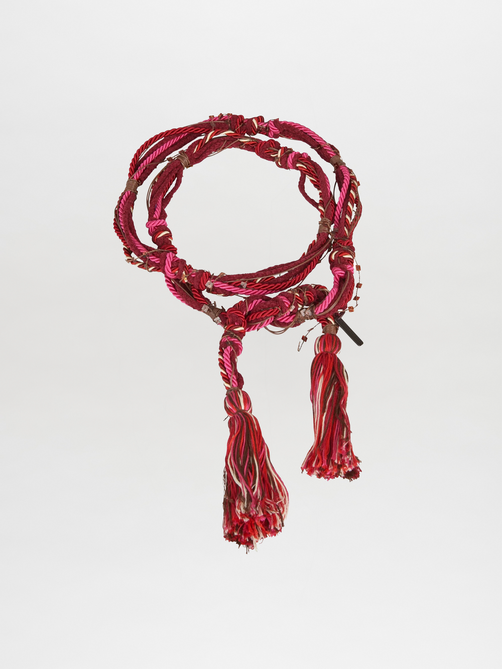 The Nellie Belt Fucshia by Silvia Tcherassi features coiled red, pink, and white threads with two large tassels—an eye-catching accessory from Pre Fall 2023, shown on a plain white background.