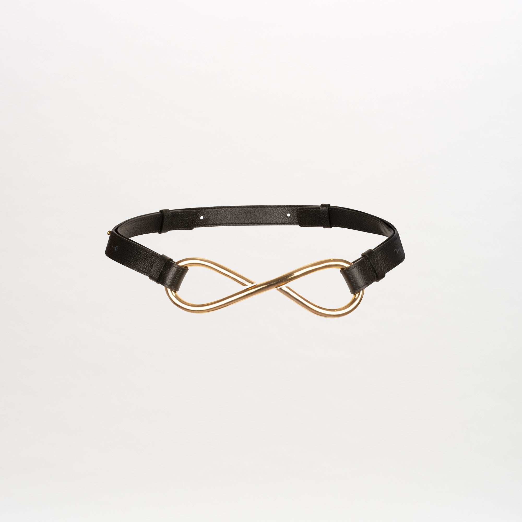 The Oihana Belt by SVT DESIGNS is a sleek black leather accessory featuring an adjustable strap and a gold-tone infinity symbol buckle, elegantly displayed against a plain white background.