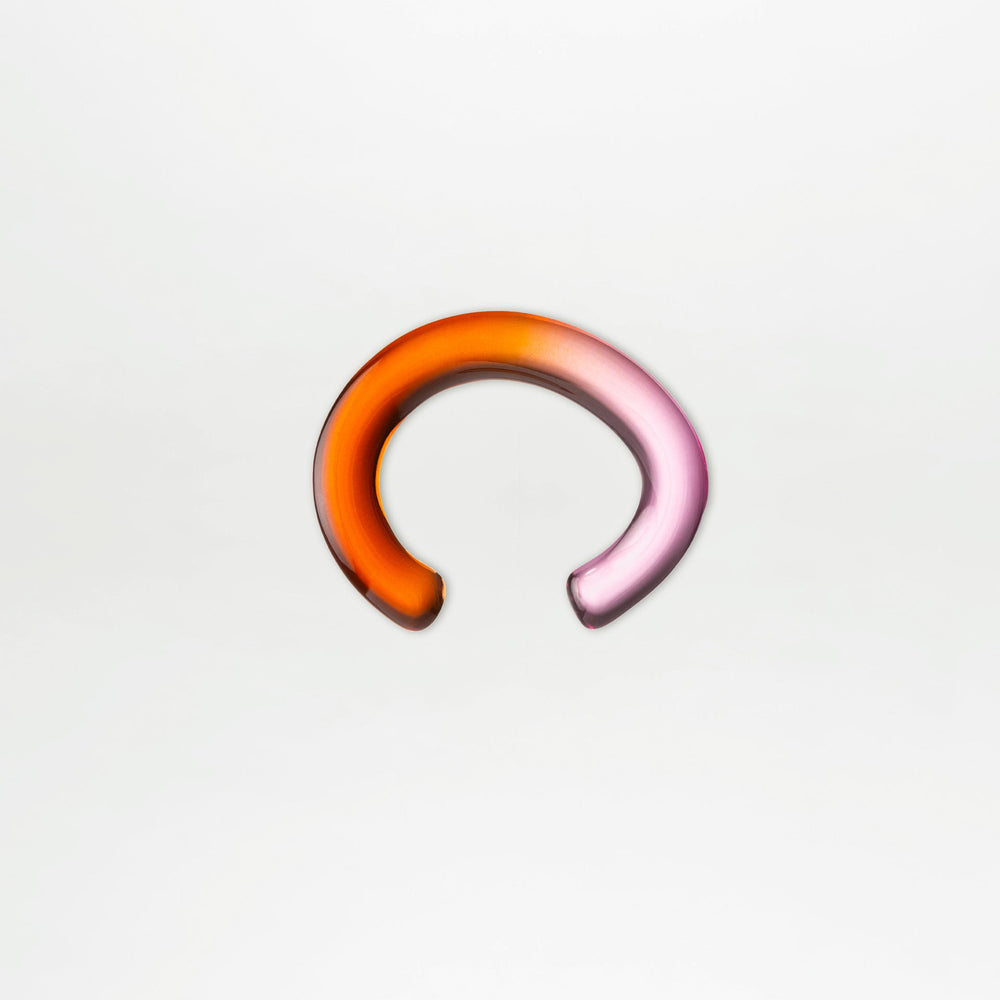 The Oli Bracelet by SVT DESIGNS is an acrylic, incomplete-circle bracelet made from Italian PMMA, featuring a glass-like finish and a gradient from orange to pink, shown on a plain white background.
