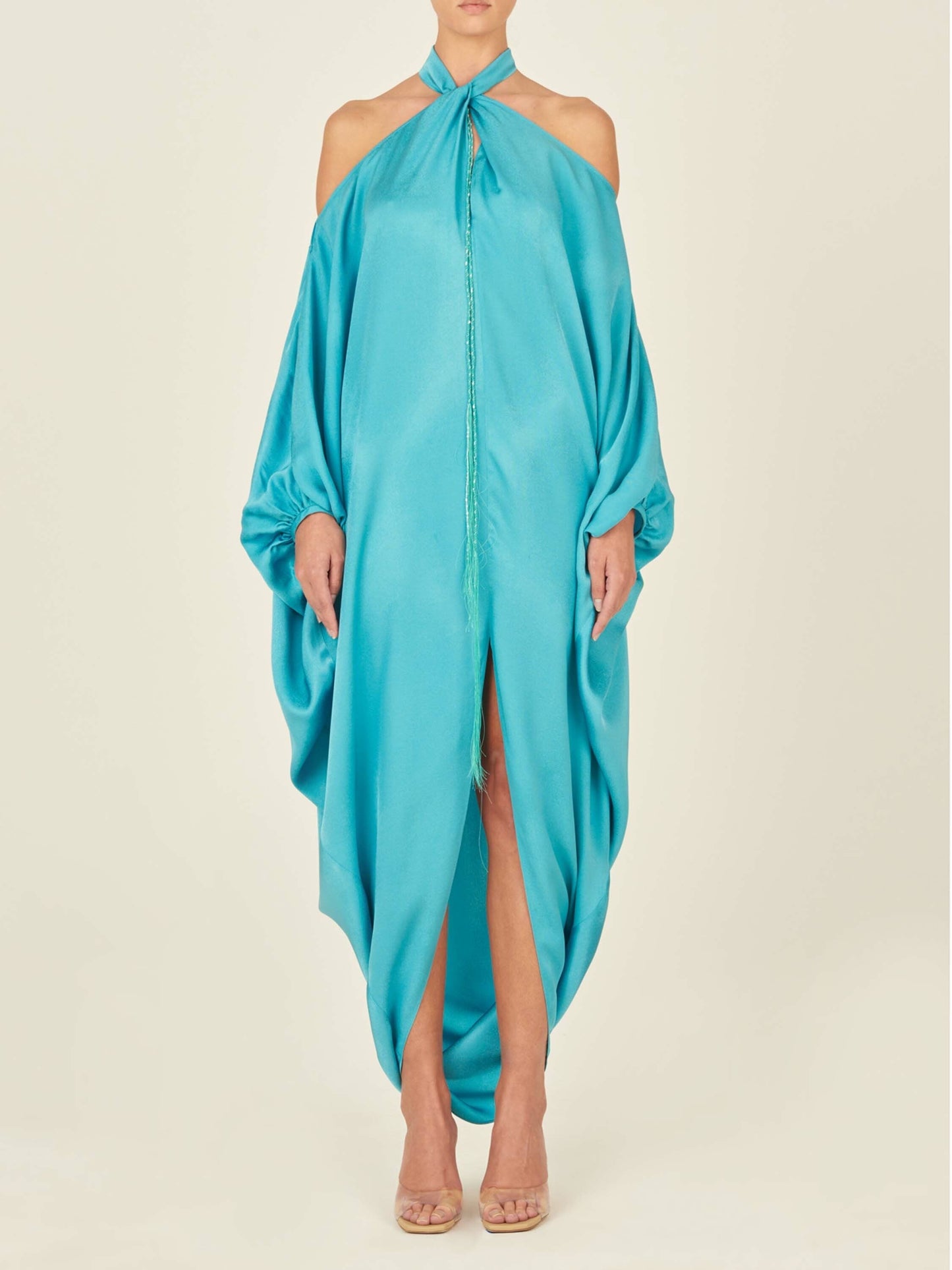 A Jacqueline Kaftan Turquoise with a halter neck and draped design, made from turquoise crepe fabric and featuring loose, flowing material.