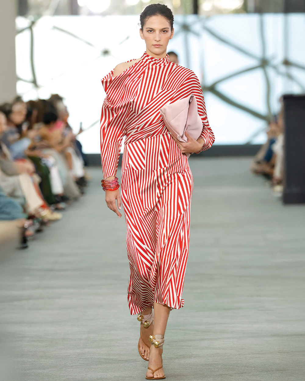 Model wearing a red and white striped dress on a fashion runway.