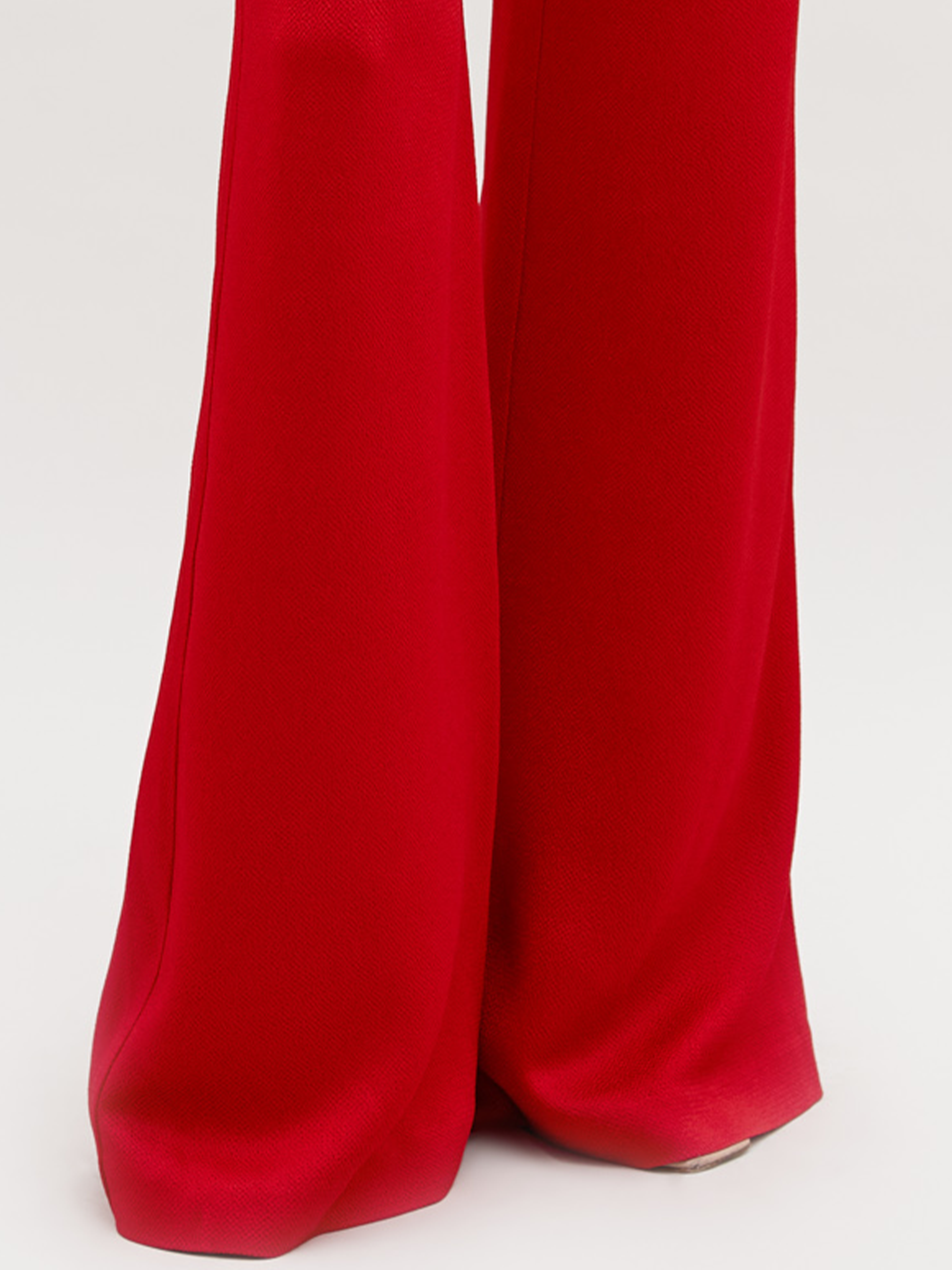 The image showcases SVT DESIGNS' Palermo Pant, featuring high-waisted, red fabric with wide, flowing legs that reach the floor against a neutral background, highlighting its relaxed silhouette.