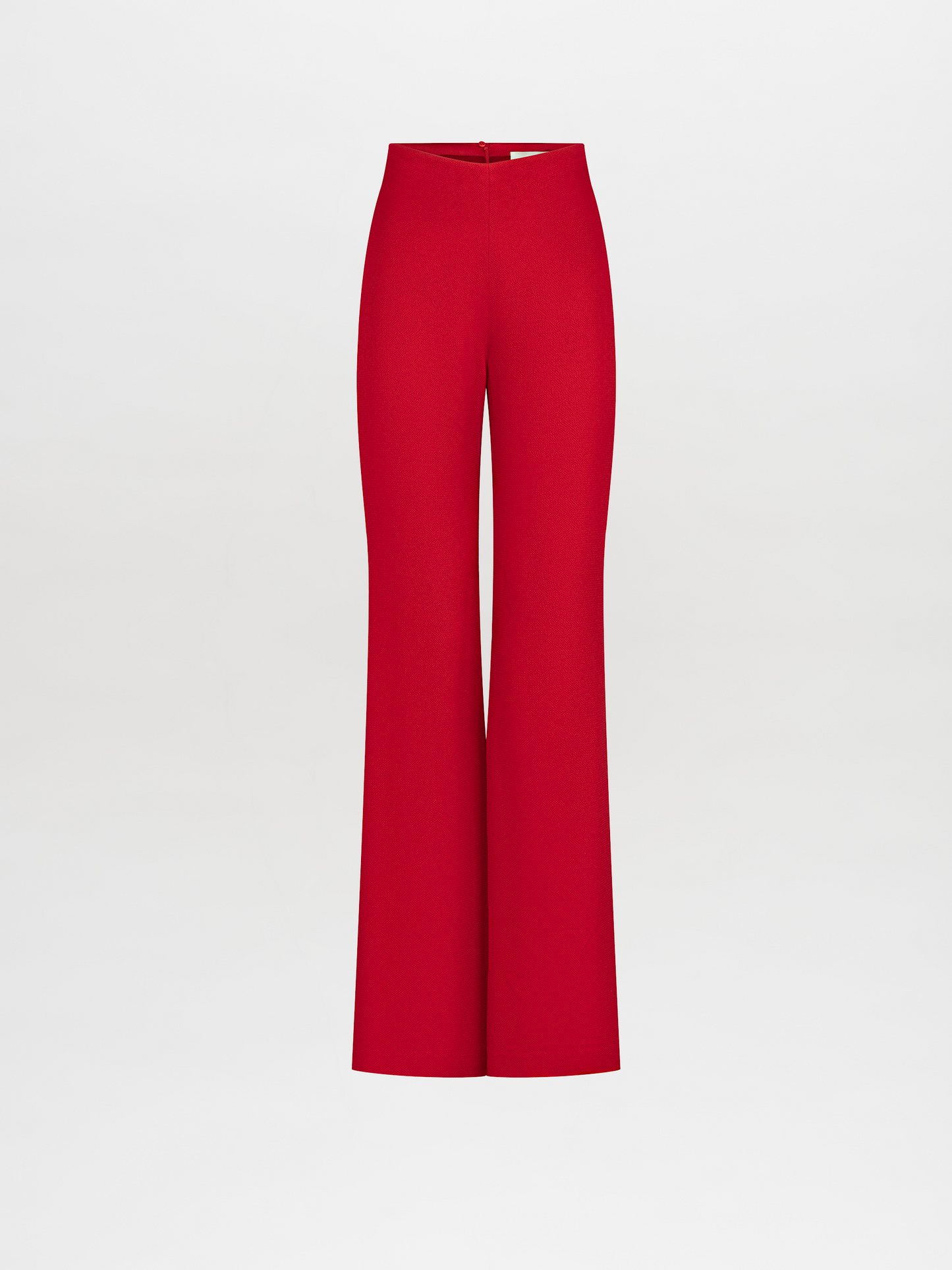 A person stands against a plain background wearing a red long-sleeved top with a knot detail at the waist and matching Palermo Pant Rouge, available for pre-order with a ship by date of November 15th, 2024.