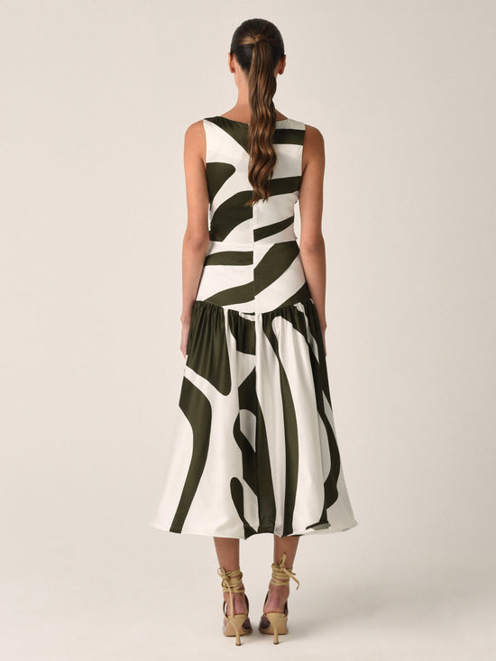 Experience elegance in the Roseanne Dress Green Abstract Palm, a sleeveless silk midi dress with a striking black and white abstract pattern. The gathered front bodice and asymmetrical hemline add an extra touch of sophistication to this timeless piece.