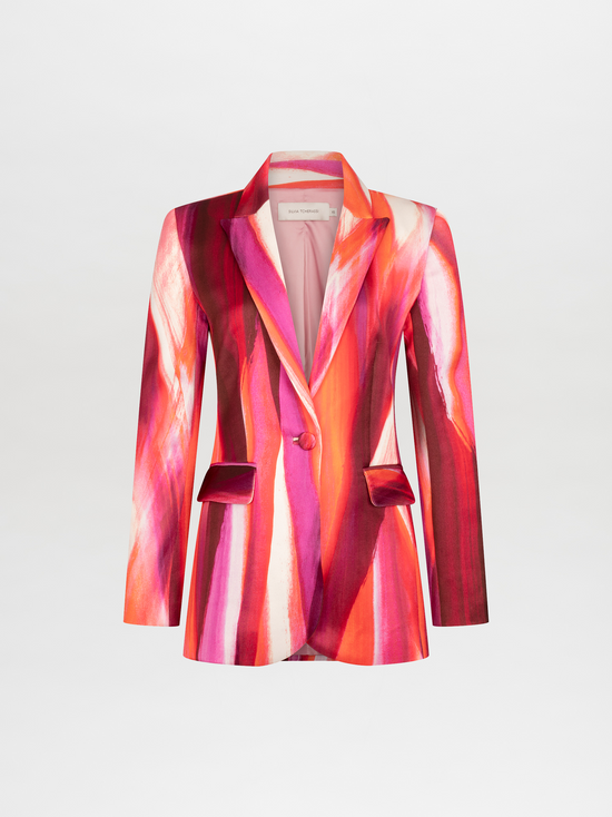 Woman wearing a vibrant, multi-colored striped Rebeca Jacket Magenta Abstract Waves with a deep neckline, accessorized with a chunky gold choker necklace, standing against a plain white background. Pre-order now and have it ship by date of November 15th, 2024.