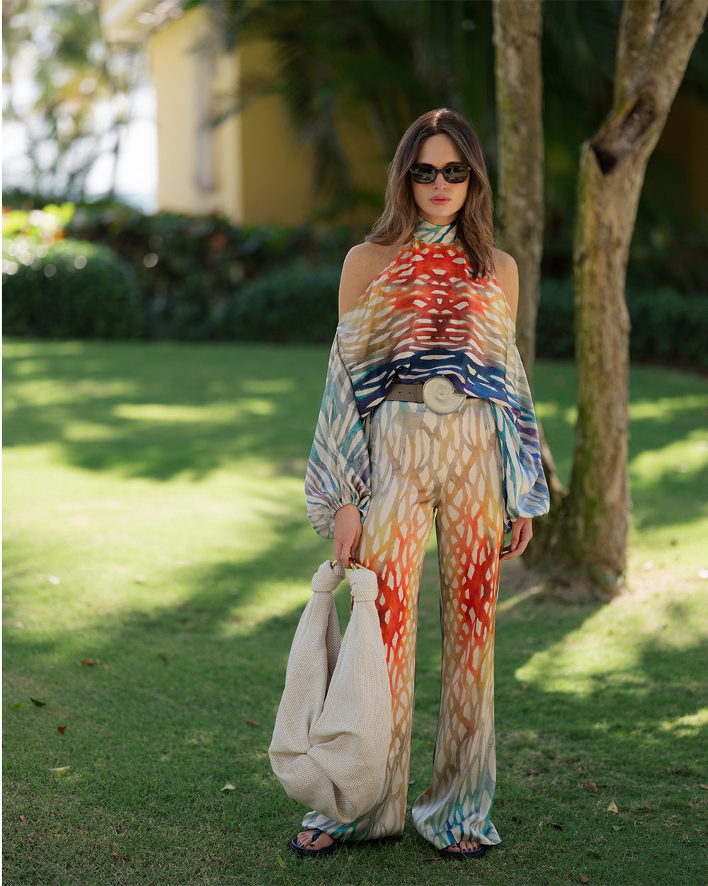 Woman in a colorful outfit standing outdoors with trees and grass in the background
