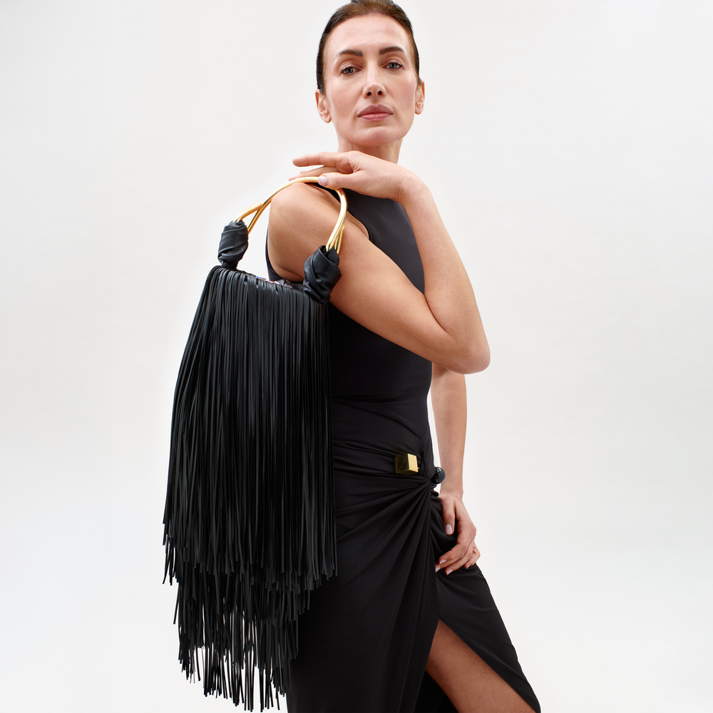 Woman holding a black fringe handbag against a white background