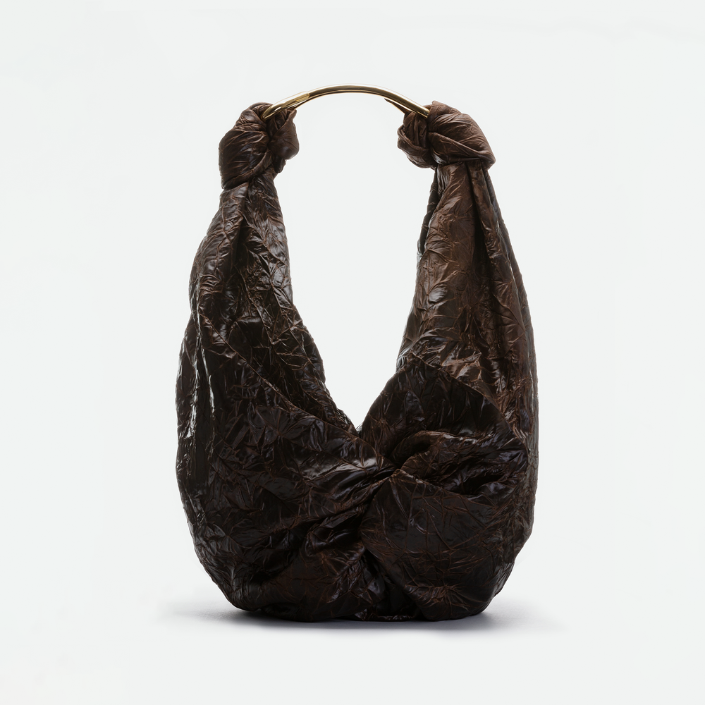 The SVT DESIGNS Sofia Bag (Maxi), featuring a brown crinkled finish, slouchy silhouette, and gold-toned curved handle, is shown against a plain white background.