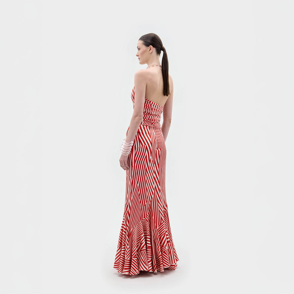 A woman with a ponytail and white bracelets on her left wrist faces away at an angle, modeling the Florina Skirt by SVT DESIGNS. The red and white striped mermaid silhouette skirt is set against a plain white background.