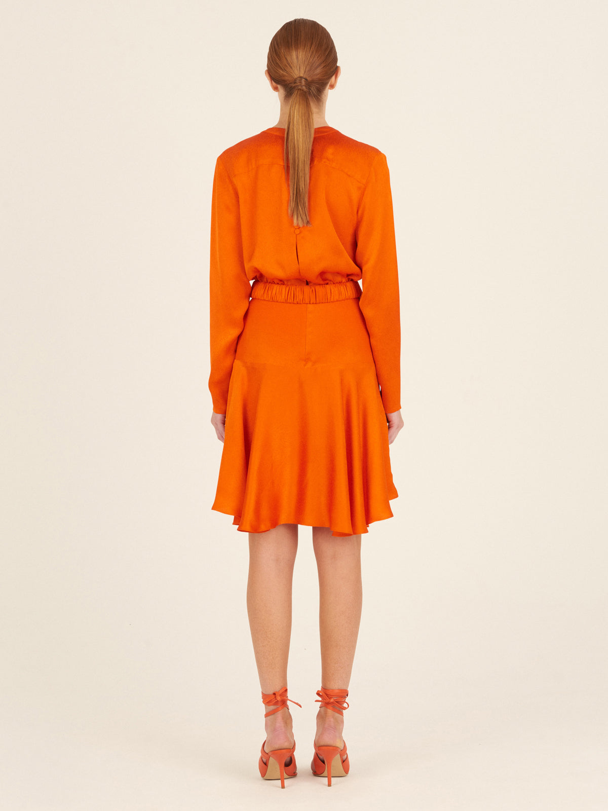 A Aglioni Dress Bright Orange mini-dress with a pink belt.