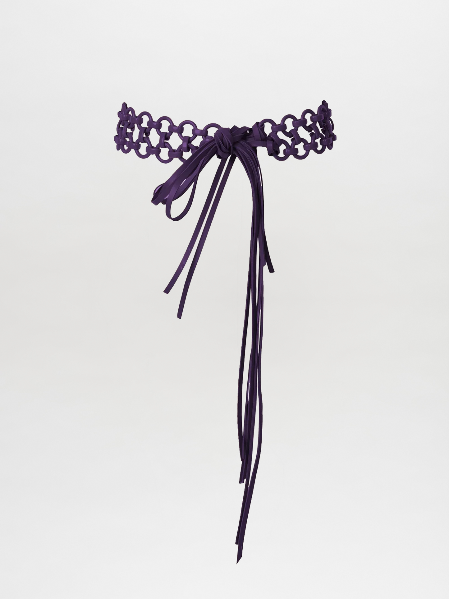 The Sindione Belt Purple features an eggplant hue and floral cut-out pattern, tied in a front bow with long ends, displayed against a plain white background.