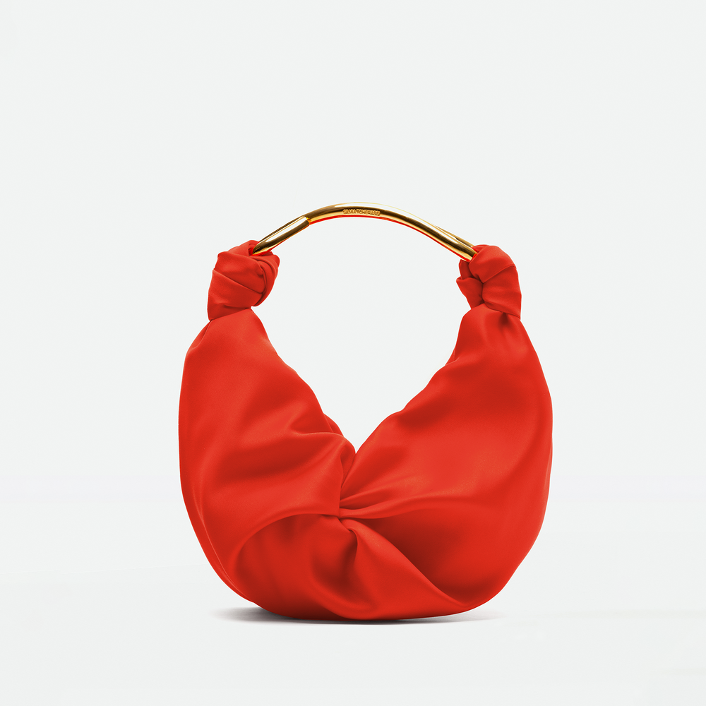 The Sofia Bag Small by SVT DESIGNS, featuring a red twisted design, gold-toned handle, and fine Italian fabric, is shown against a plain light background.