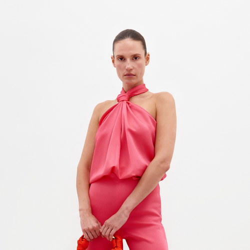 A person models the Teagan Blouse and matching pants from SVT DESIGNS against a plain white background, holding a bright red rope accessory.