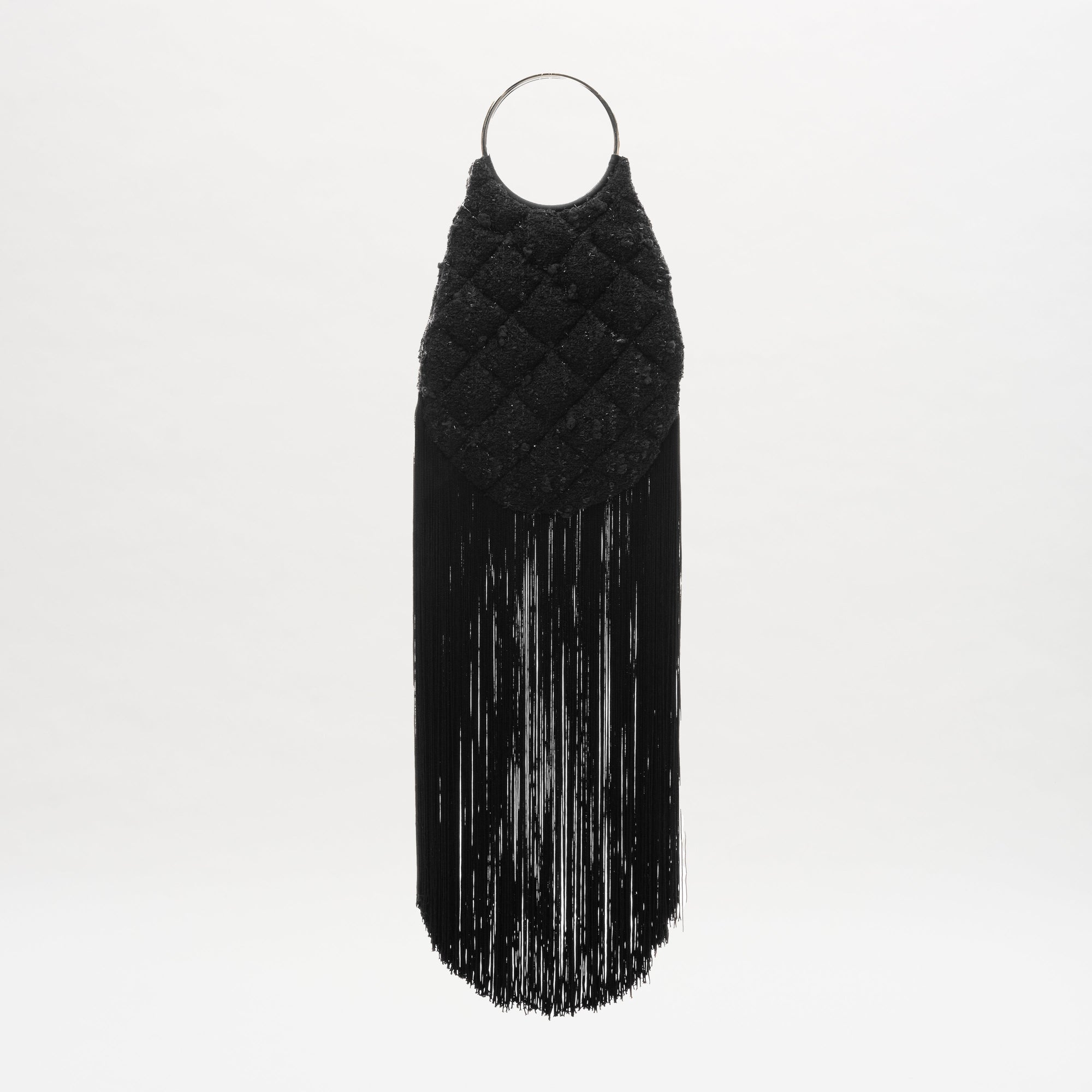 The Toblach Bag by SVT DESIGNS is a black, oval metalized cotton bag with a quilted top, long straight fringe at the bottom, and circular metallic top handles. It's displayed against a plain white background.