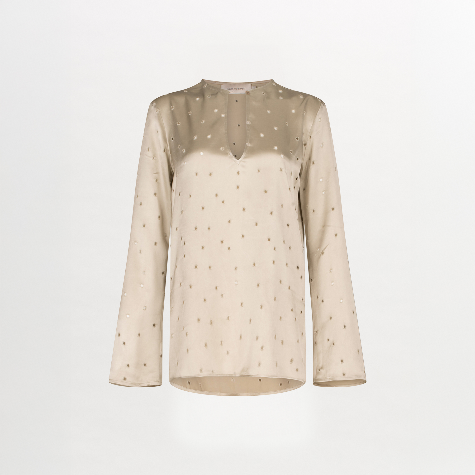The Tosca Blouse by Silvia Tcherassi US is a beige, long-sleeved Colombian top featuring a subtle dotted pattern, round keyhole neckline with front slit, and a smooth, slightly shiny finish for an elegant textured look.