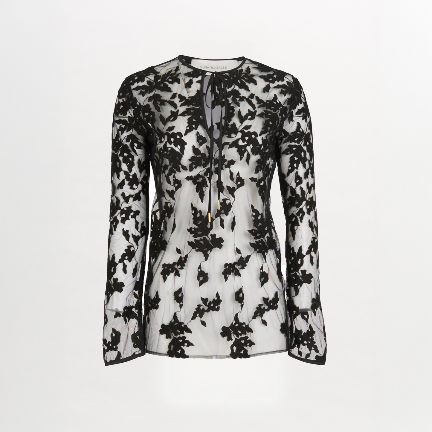 The Tosca Blouse Black Velvet by Silvia Tcherassi is a sheer silk blouse with black floral embroidery, a round neckline, keyhole opening, and neck tie, set against a plain white background.