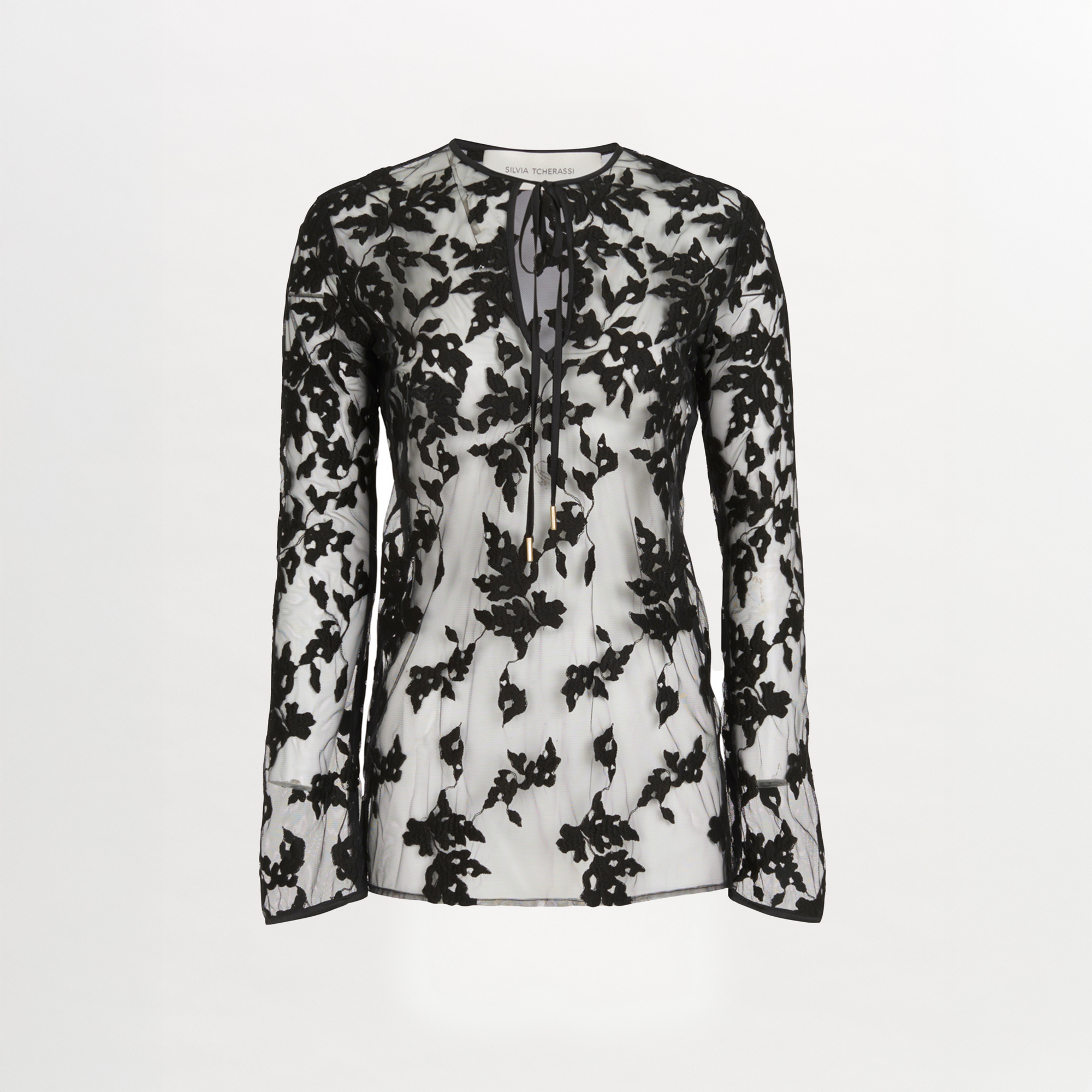The Tosca Blouse Black Velvet by Silvia Tcherassi is a sheer silk blouse with black floral embroidery, a round neckline, keyhole opening, and neck tie, set against a plain white background.