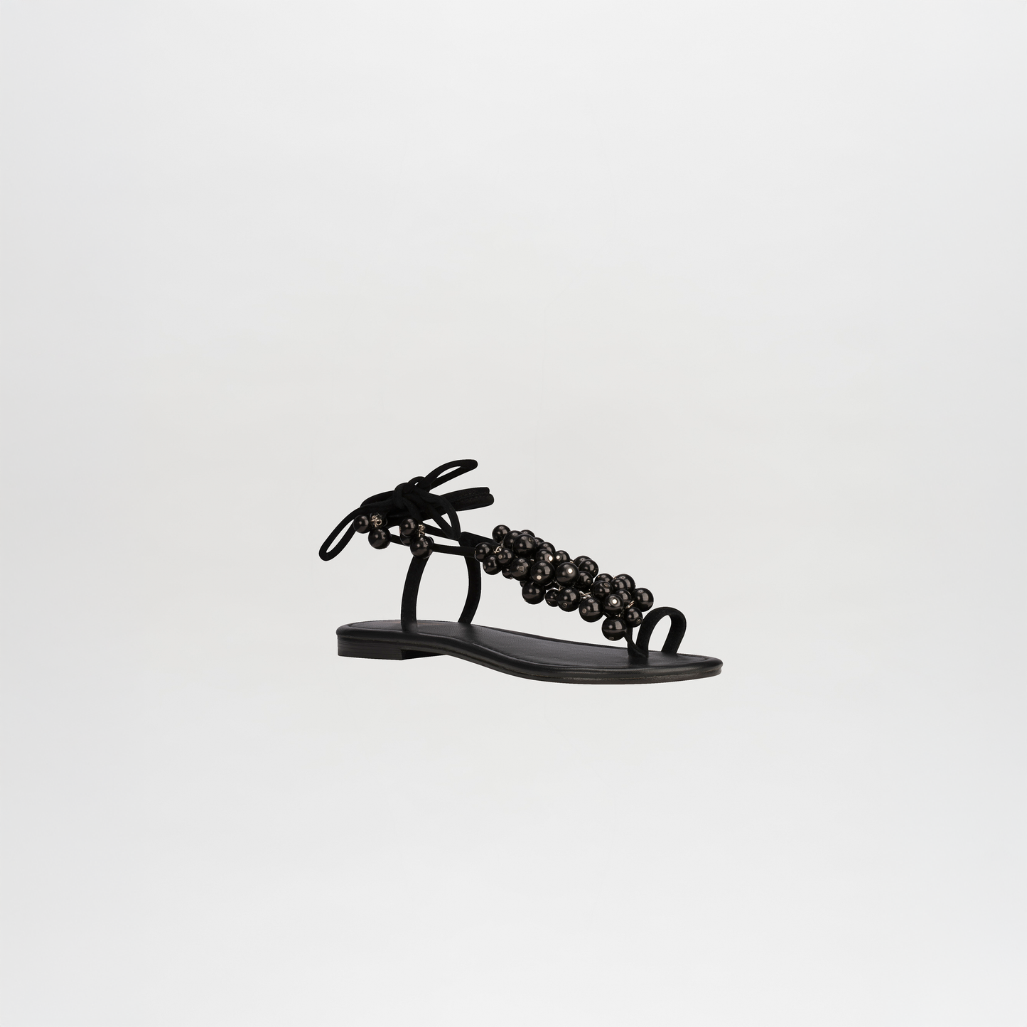 The Zaira Sandals by SVT DESIGNS feature black leather, a thin sole, open toe, ankle tie, and front strap embellishments, shown on a plain white background.