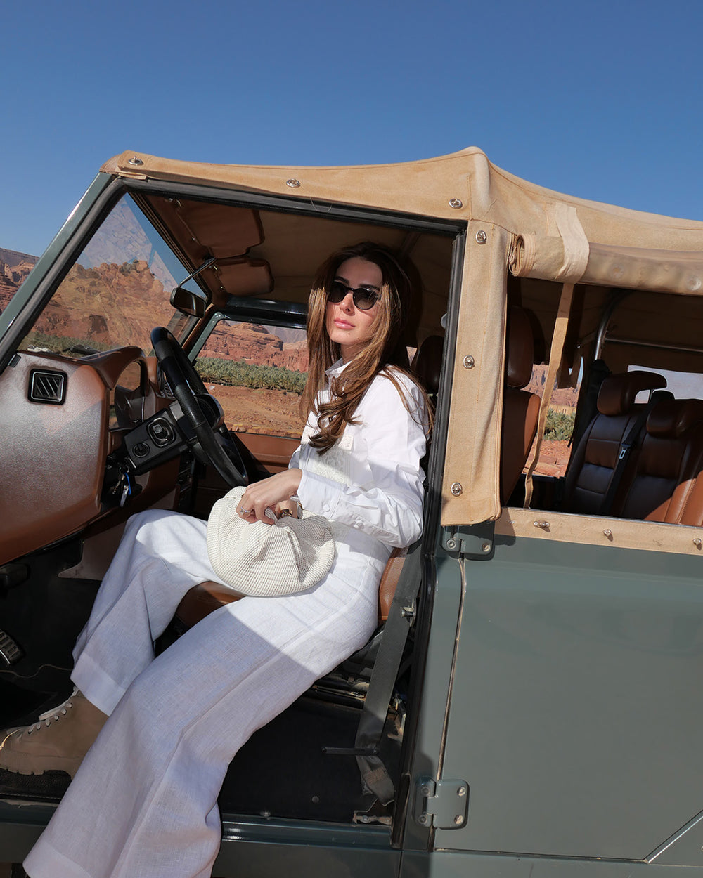 Woman sitting in an open-top vehicle with a desert landscape in the background