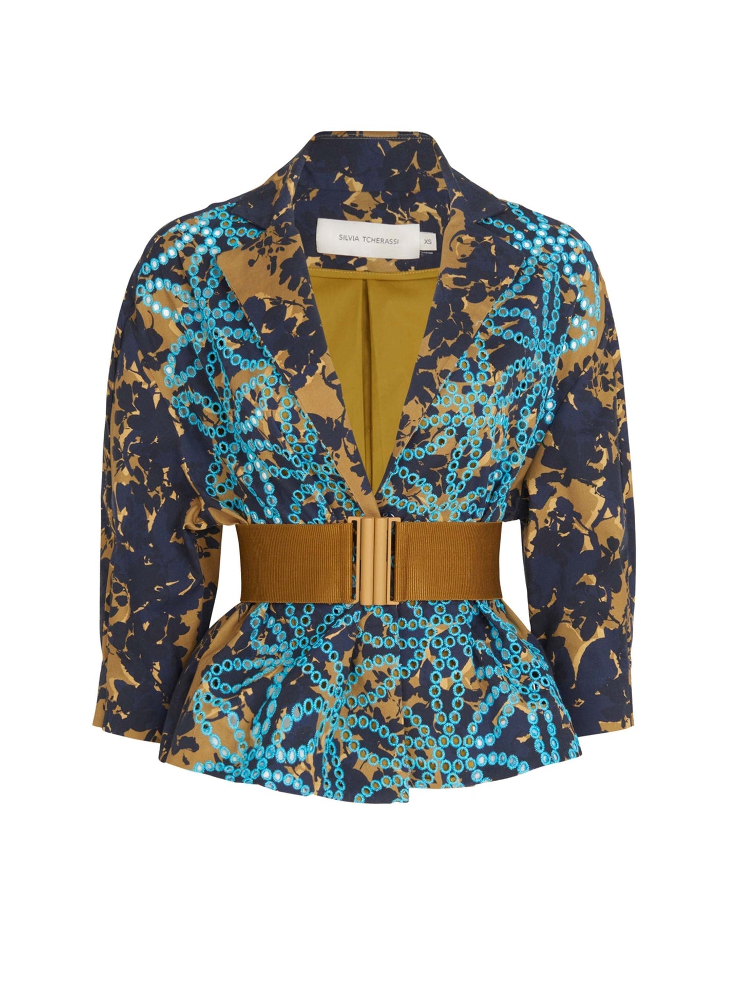 Juana Jacket Camo Navy with a geometric blue and gold pattern, featuring a wide tan belt and a double-breasted design. The cropped sleeves add a modern touch, while the interior lining is mustard yellow.