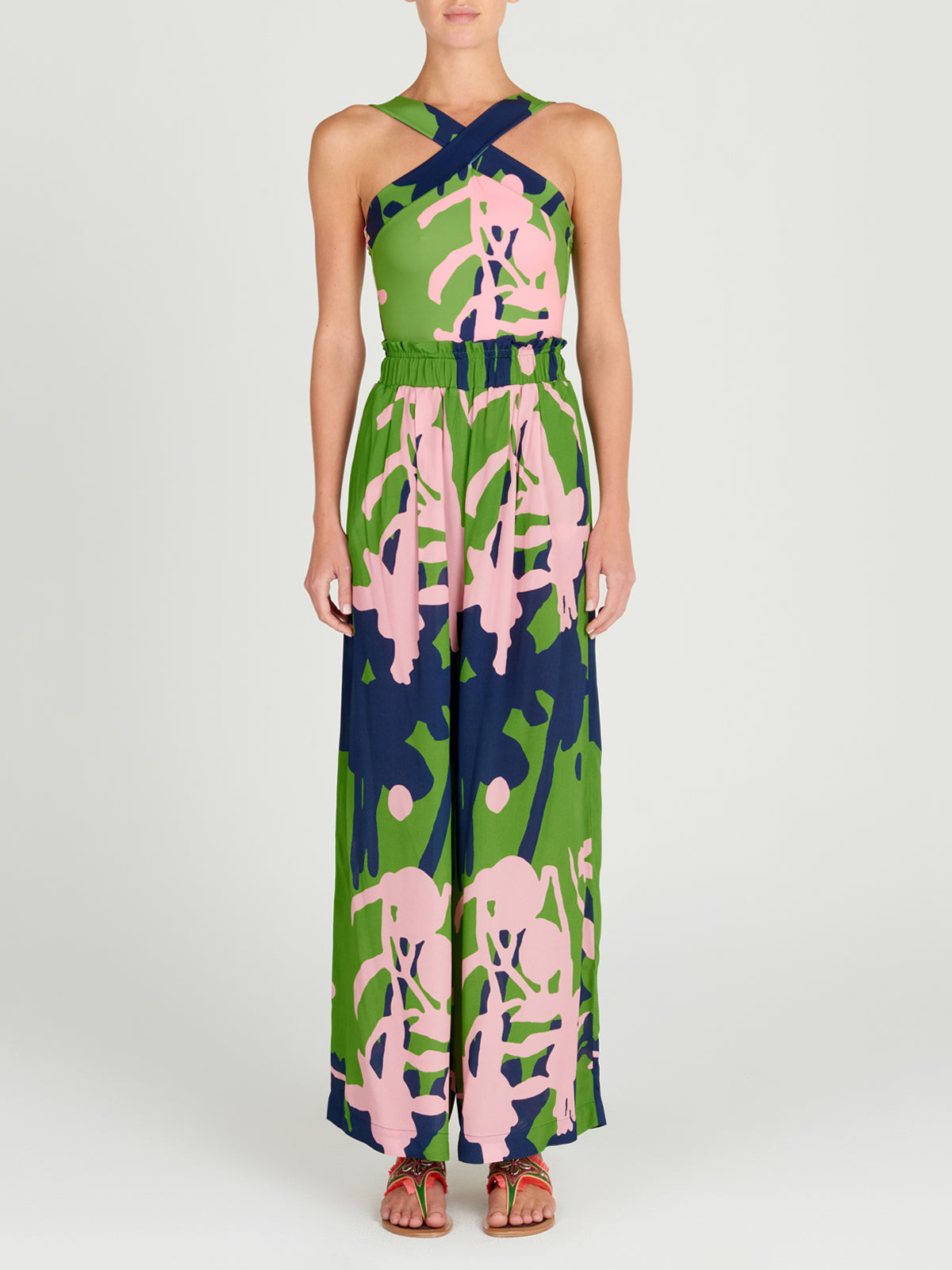 A person stands facing forward in the Silvia Tcherassi Ovada Pant, featuring wide legs and an elastic waistband with a green, navy, and pink abstract print, paired with flat sandals.